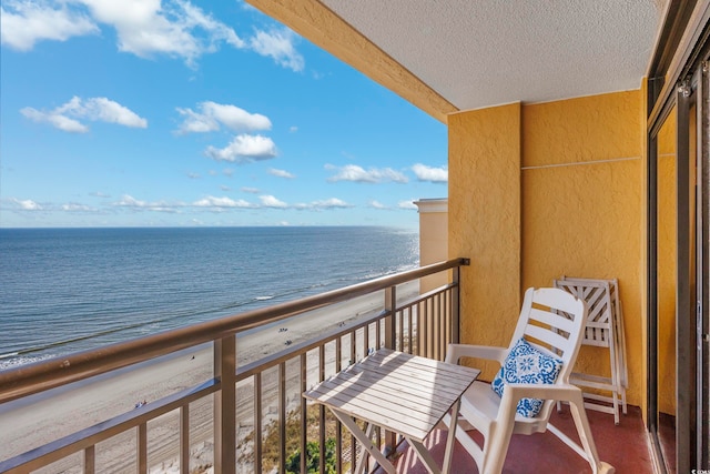 balcony featuring a view of the beach and a water view