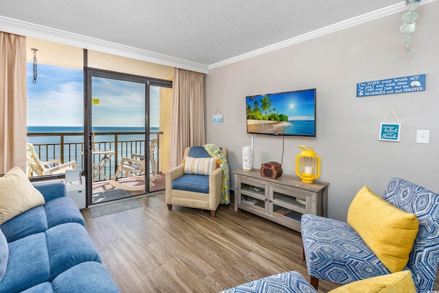 living room with a wealth of natural light, a water view, a textured ceiling, and light wood-type flooring