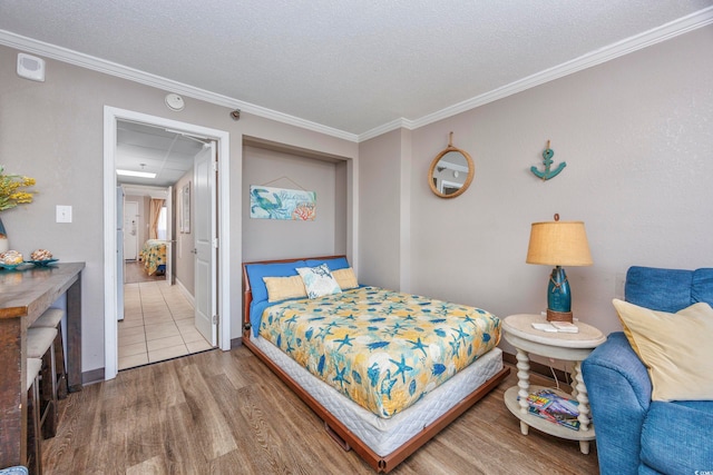 bedroom with hardwood / wood-style flooring, ornamental molding, and a textured ceiling