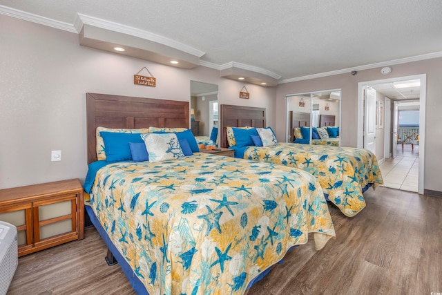 bedroom featuring a textured ceiling, wood-type flooring, crown molding, and a closet