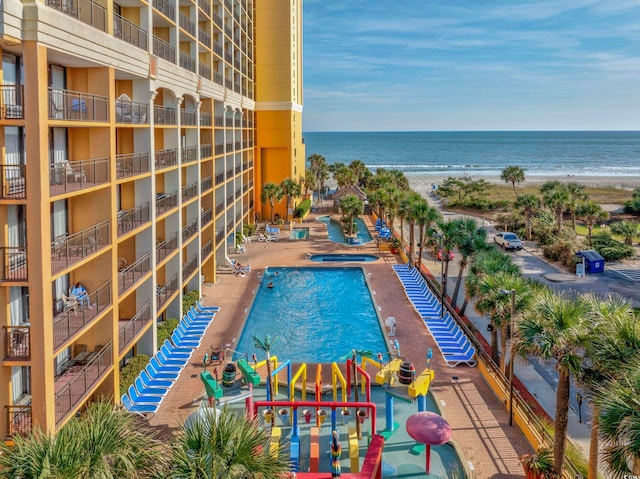 view of swimming pool with a water view and a beach view