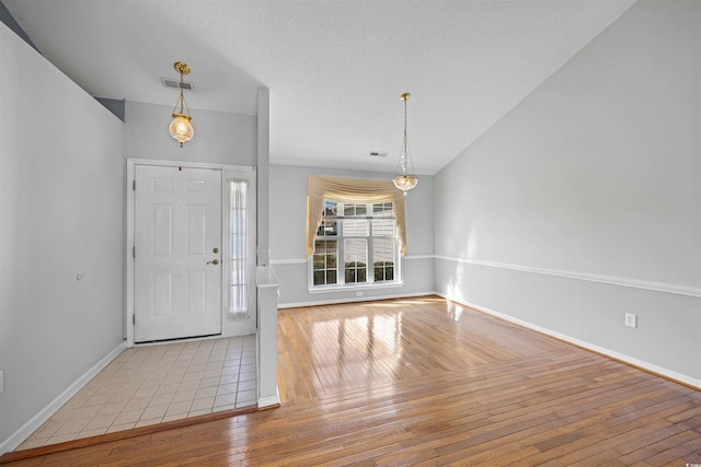 foyer featuring a textured ceiling, light hardwood / wood-style flooring, and lofted ceiling