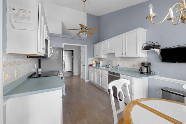 kitchen featuring appliances with stainless steel finishes, ceiling fan with notable chandelier, pendant lighting, wood-type flooring, and white cabinetry