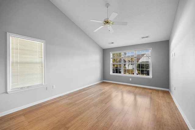 empty room with a textured ceiling, light wood-type flooring, high vaulted ceiling, and ceiling fan