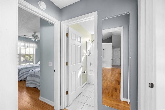 hallway with a textured ceiling and light hardwood / wood-style flooring