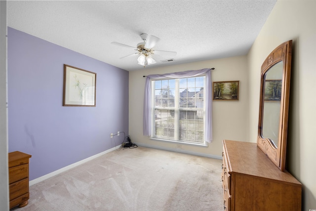 interior space featuring ceiling fan, light colored carpet, and a textured ceiling