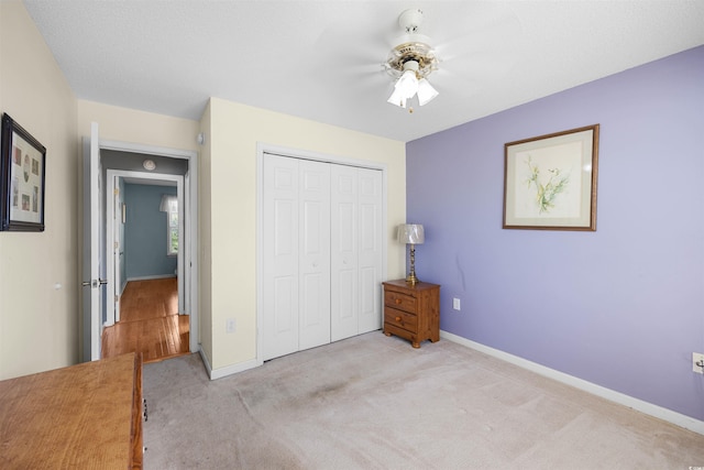 unfurnished bedroom featuring light carpet, a closet, and ceiling fan