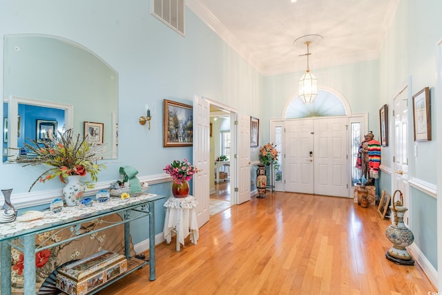 foyer with a high ceiling, light hardwood / wood-style floors, and crown molding