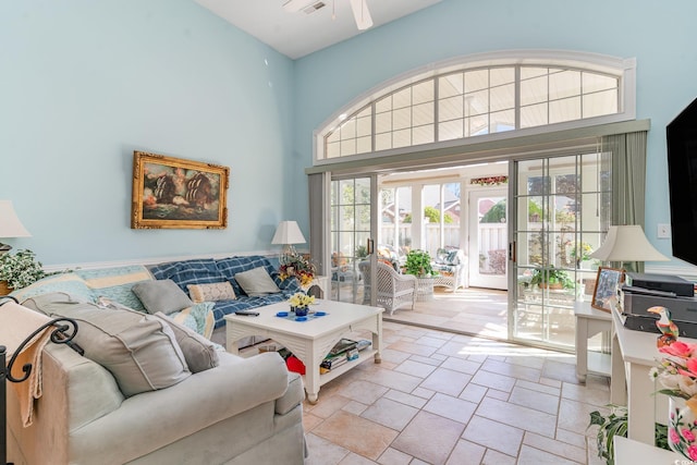 living room with ceiling fan and a towering ceiling