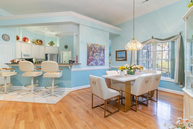 dining area with ceiling fan with notable chandelier, light hardwood / wood-style flooring, and ornamental molding