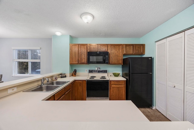 kitchen featuring sink, black appliances, kitchen peninsula, and a textured ceiling