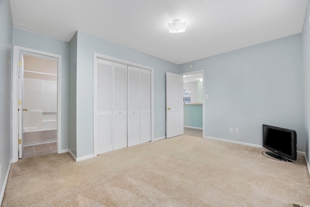 unfurnished bedroom with light colored carpet, a textured ceiling, and a closet