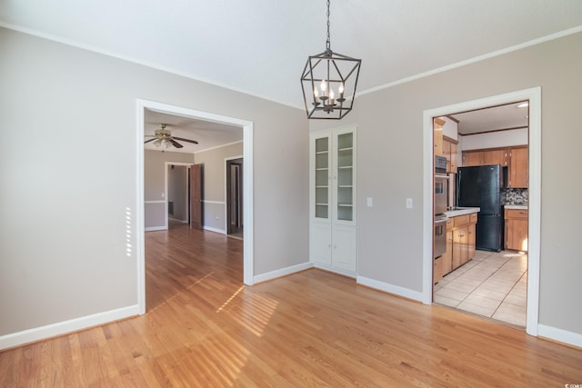 empty room featuring light hardwood / wood-style floors, ceiling fan with notable chandelier, and ornamental molding