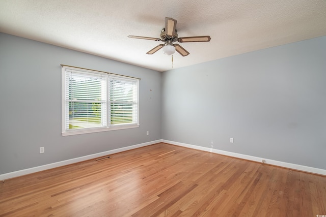 empty room featuring ceiling fan, light wood-type flooring, and a textured ceiling