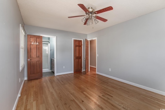 unfurnished bedroom featuring ceiling fan, light wood-type flooring, a textured ceiling, and connected bathroom