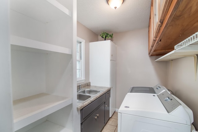 washroom featuring sink, cabinets, separate washer and dryer, a textured ceiling, and light tile patterned floors