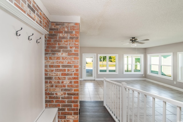 interior space with tile patterned flooring, a textured ceiling, a wealth of natural light, and ceiling fan