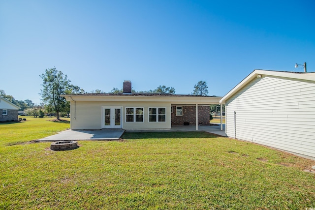 rear view of property featuring french doors, a yard, a fire pit, and a patio area