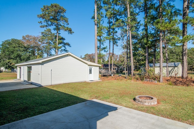 view of yard featuring a fire pit, a patio area, and an outbuilding