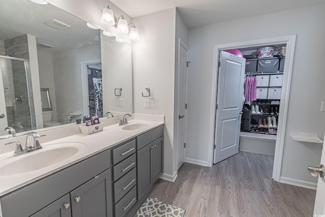 bathroom featuring vanity, hardwood / wood-style flooring, toilet, and an enclosed shower