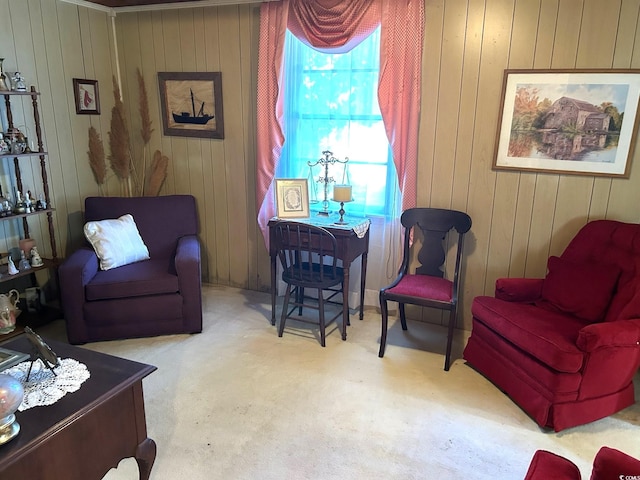 sitting room featuring wood walls and light carpet