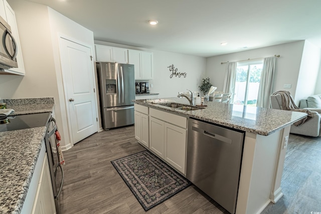 kitchen with stainless steel appliances, dark wood-type flooring, sink, white cabinets, and an island with sink