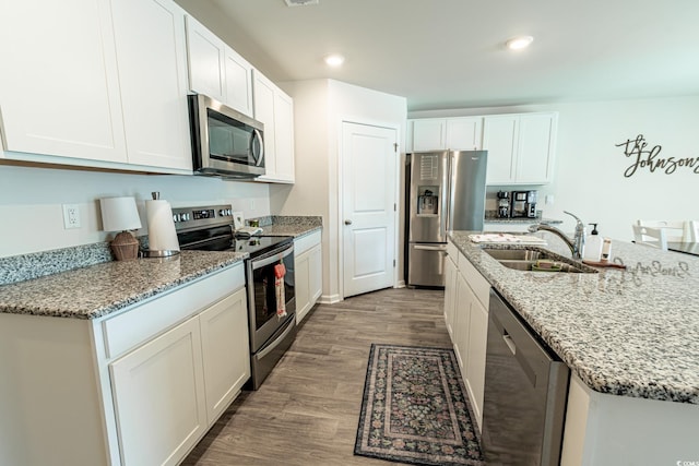 kitchen featuring white cabinets, sink, dark hardwood / wood-style floors, light stone counters, and stainless steel appliances