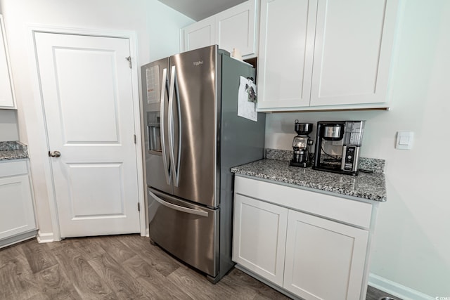 kitchen with stone countertops, wood-type flooring, white cabinetry, and stainless steel refrigerator with ice dispenser