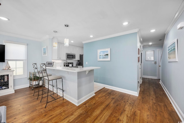 209 N Hillside Dr Unit 201, North Myrtle Beach, SC 29582 - kitchen with stainless steel microwave, a breakfast bar, a peninsula, crown molding, and white cabinets