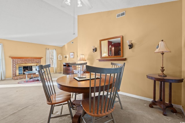 dining area with ceiling fan, a brick fireplace, high vaulted ceiling, a textured ceiling, and carpet