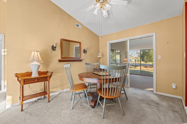 dining area with ceiling fan, high vaulted ceiling, light colored carpet, and a textured ceiling