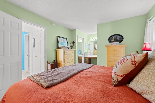 bedroom with ensuite bathroom and a textured ceiling