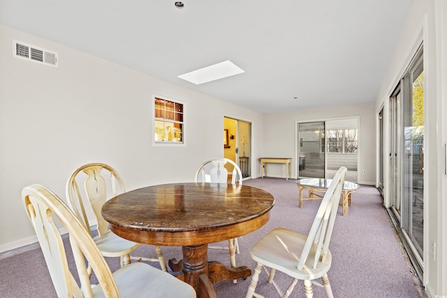 carpeted dining area featuring a skylight