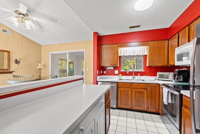 kitchen featuring appliances with stainless steel finishes, a textured ceiling, ceiling fan, sink, and light tile patterned floors