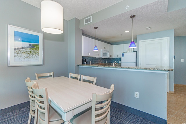 dining area with a textured ceiling, sink, and light tile patterned flooring