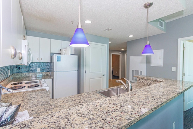 kitchen featuring white appliances, backsplash, white cabinets, sink, and hanging light fixtures