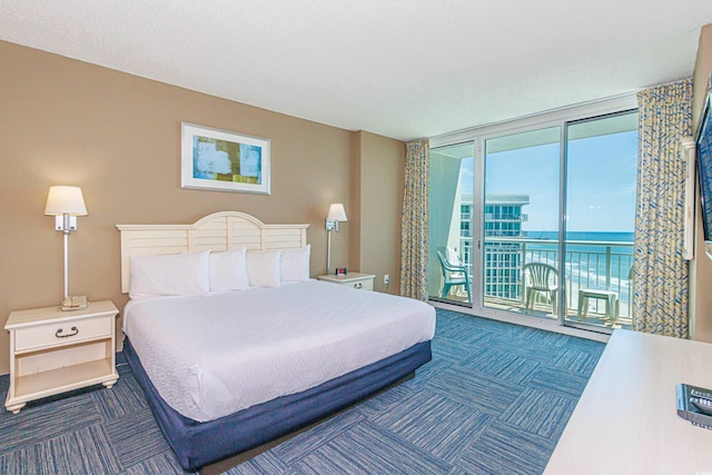 bedroom featuring access to exterior, a water view, and a wall of windows