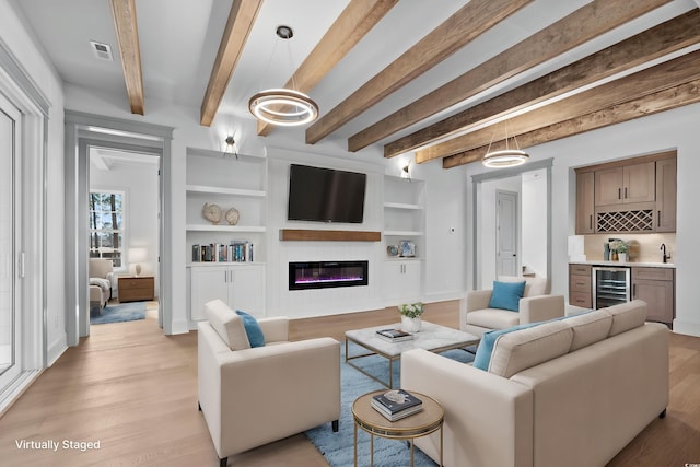 living room with beam ceiling, built in shelves, indoor bar, and beverage cooler