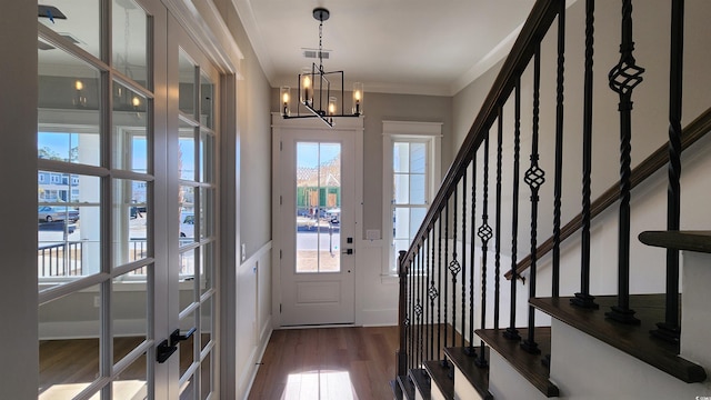 foyer featuring dark hardwood / wood-style flooring, an inviting chandelier, and ornamental molding