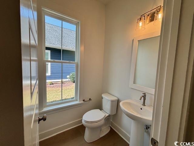 bathroom with healthy amount of natural light, baseboards, toilet, and wood finished floors