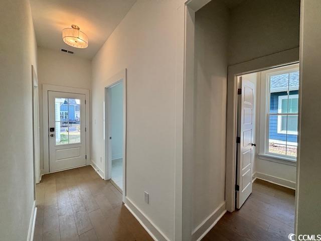 doorway with dark wood-style floors and baseboards