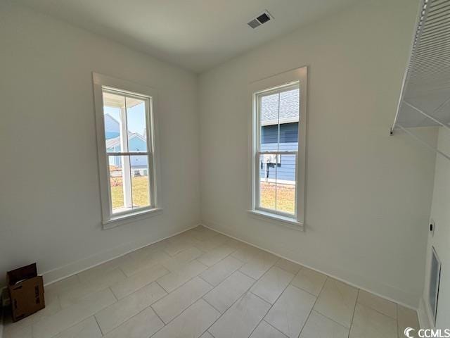 empty room featuring healthy amount of natural light, baseboards, and light tile patterned floors