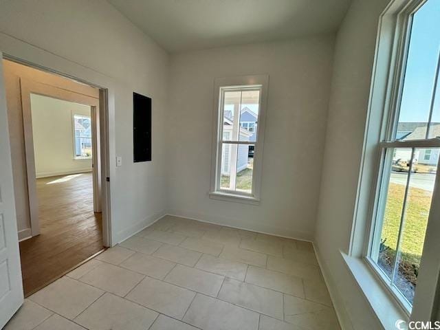 spare room with healthy amount of natural light, baseboards, and light tile patterned floors