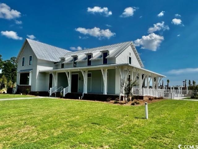 farmhouse with covered porch, a front yard, and metal roof