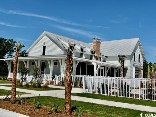 view of front of home featuring a chimney, a porch, fence, and metal roof