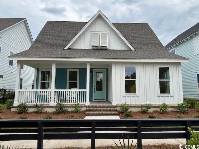 734 Macon Aly, Myrtle Beach, SC 29588 - view of front of home featuring board and batten siding, a porch, a fenced front yard, and a shingled roof