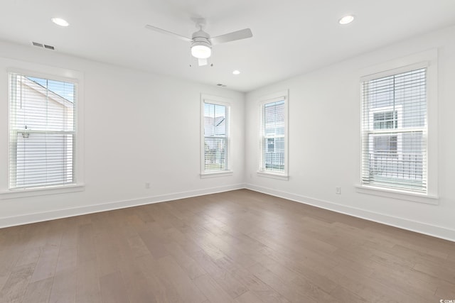 empty room featuring dark wood-style flooring, recessed lighting, visible vents, a ceiling fan, and baseboards