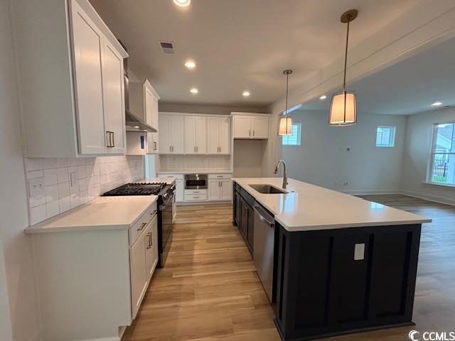 734 Macon Aly, Myrtle Beach, SC 29588 - kitchen with wall chimney range hood, stainless steel gas stove, wood finished floors, light countertops, and baseboards
