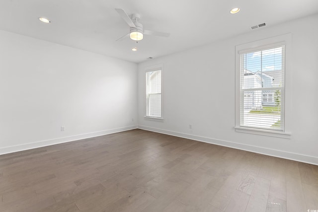 unfurnished room featuring a ceiling fan, dark wood-style flooring, visible vents, and baseboards