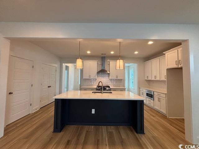 734 Macon Aly, Myrtle Beach, SC 29588 - kitchen featuring wall chimney range hood, tasteful backsplash, white cabinets, dark wood-style floors, and light countertops